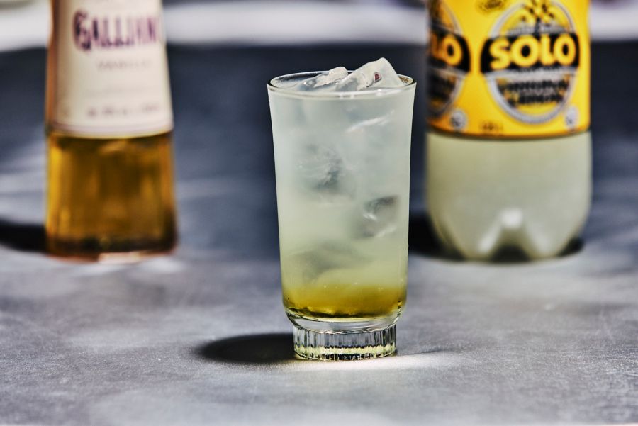 Solo and Galliano in a glass filled with ice, with the bottles of each behind it