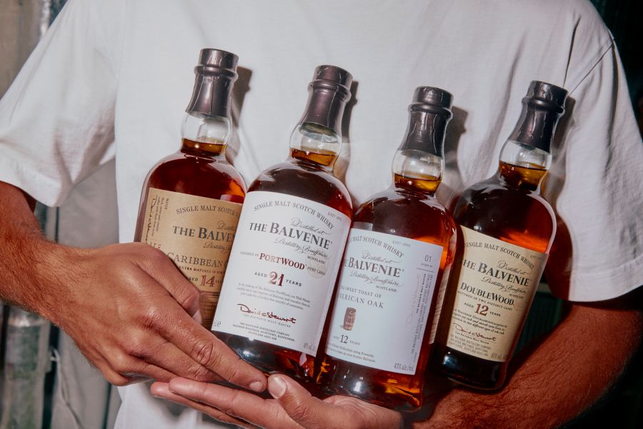 Holding four bottles of The Balvenie Scotch whisky