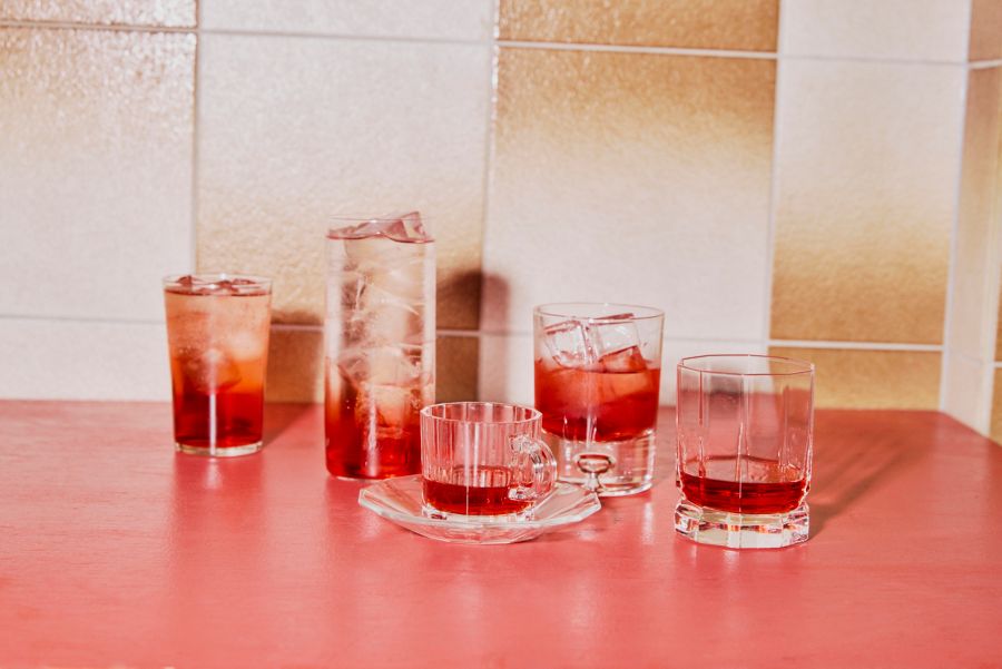 Various drinks on a red counter all made with bitter red liqueurs 