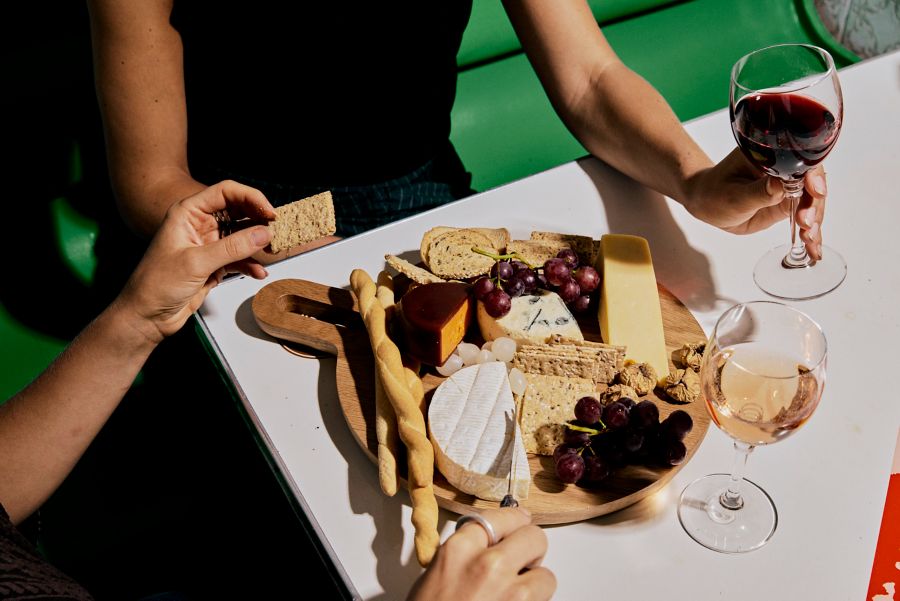 Two people enjoying a cheese board with a glass of wine