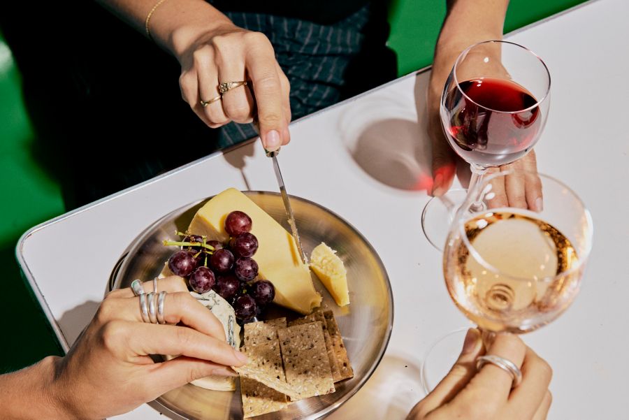 Cutting into cheese on a plate sitting next to grapes and crackers