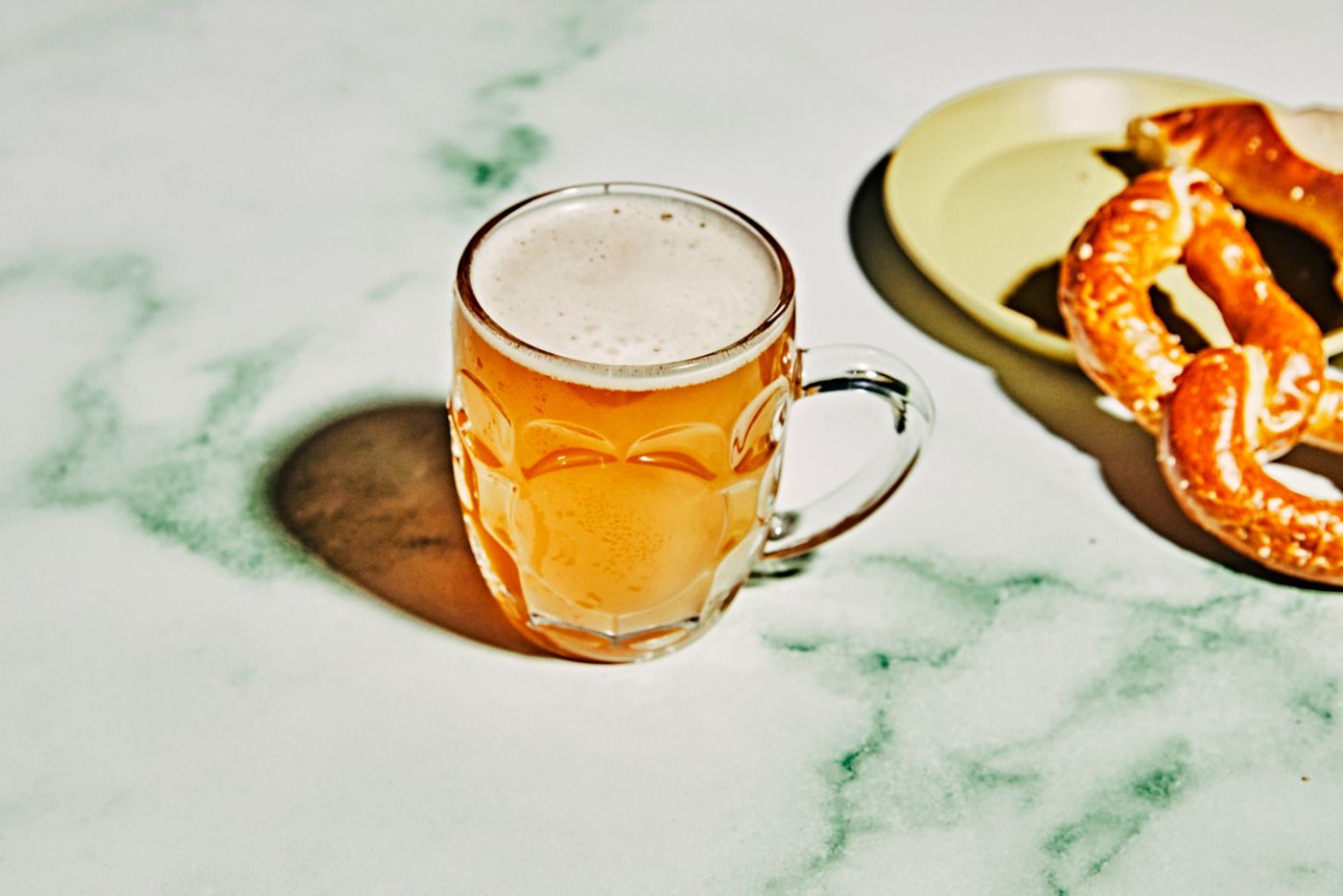 A pint of beer with a pretzel on a table