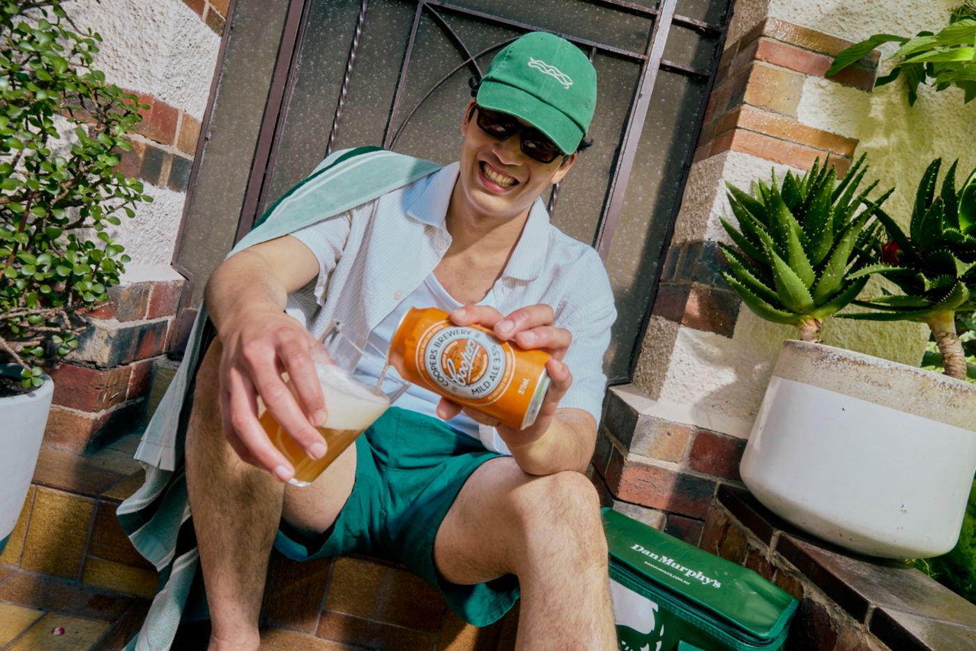Pouring a zero%* beer on a step outside a house