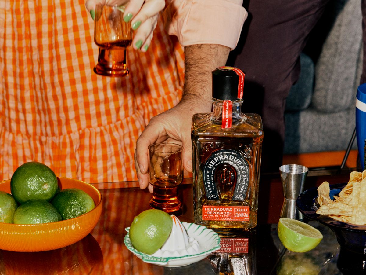 Table with Herradura Reposado Tequila bottle and limes