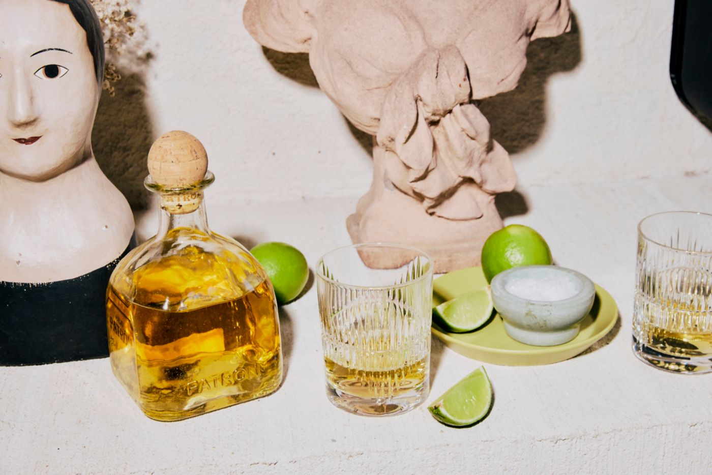 A bottle of Patron añejo tequila with glasses and limes 