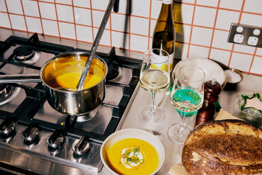 Creamy pumpkin soup on the stovetop with a glass of white wine