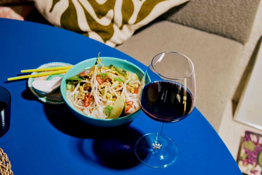 A bowl of beef pho with a glass of pinot noir