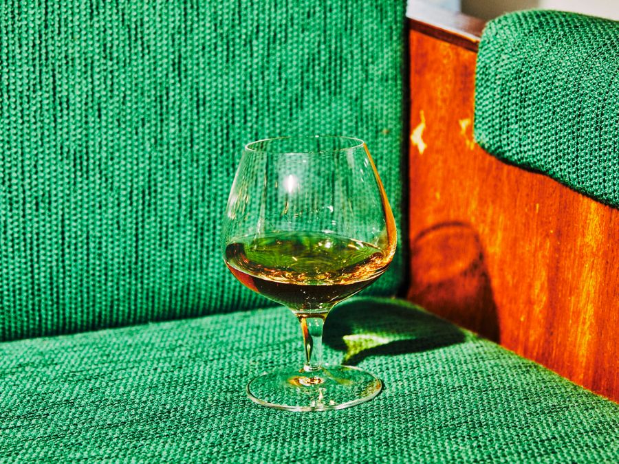 A baloon glass of Cognac on a green couch 