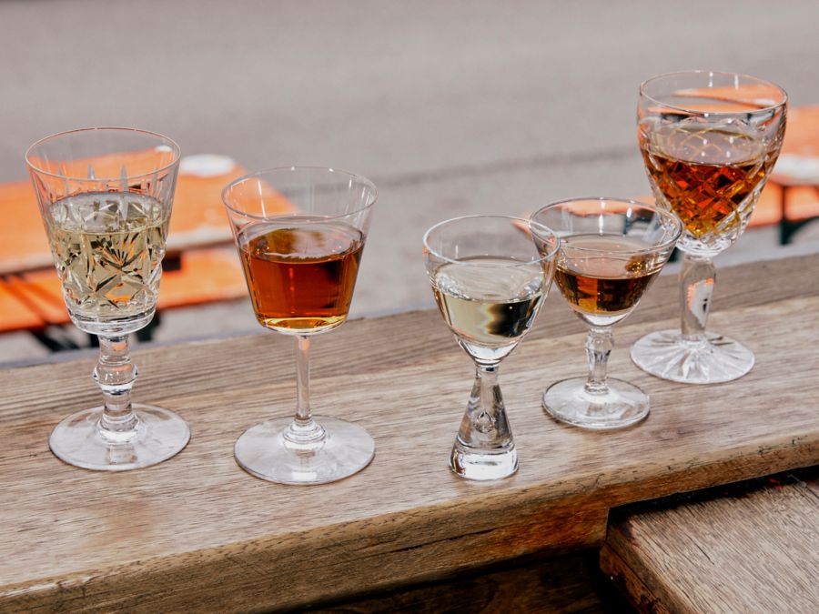 Various styles of sherry lined up on a railing at a pub 