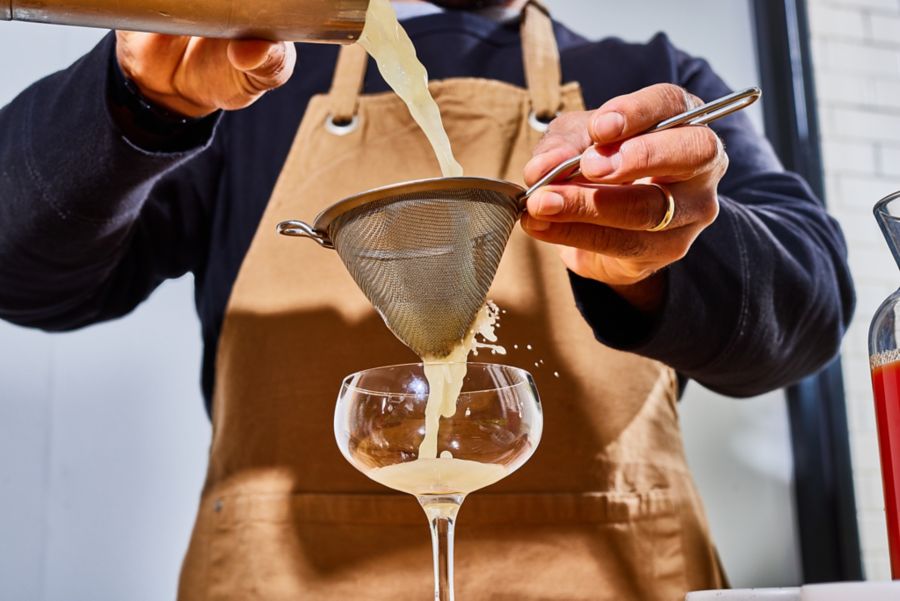 Straining a cocktail into a coupe glass