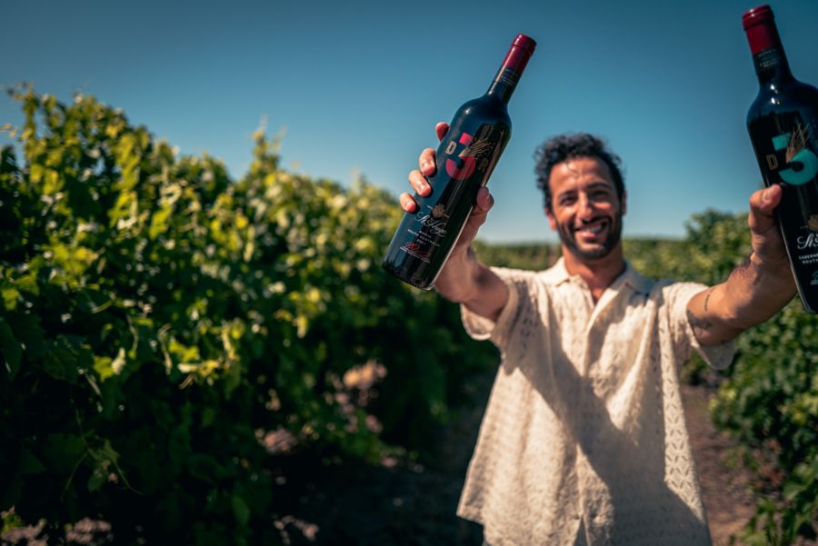 F1 champion Daniel Ricciardo holding up two of his new DR3 x St Hugo wines 