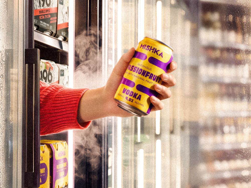 A hand coming out of a fridge holding the new Mishka Passionfruit Vodka