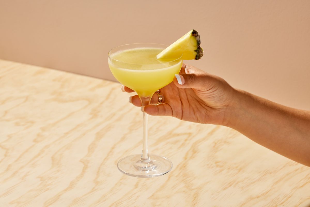 Holding a Pineapple Daiquri with a pineapple wedge as garnish