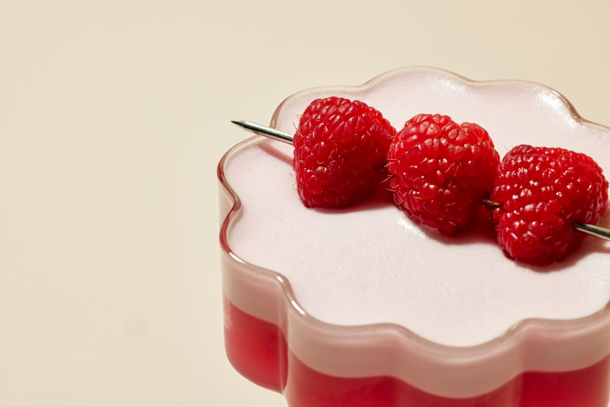 Close up shot of The Clover Club cocktail in a glass with raspberries
