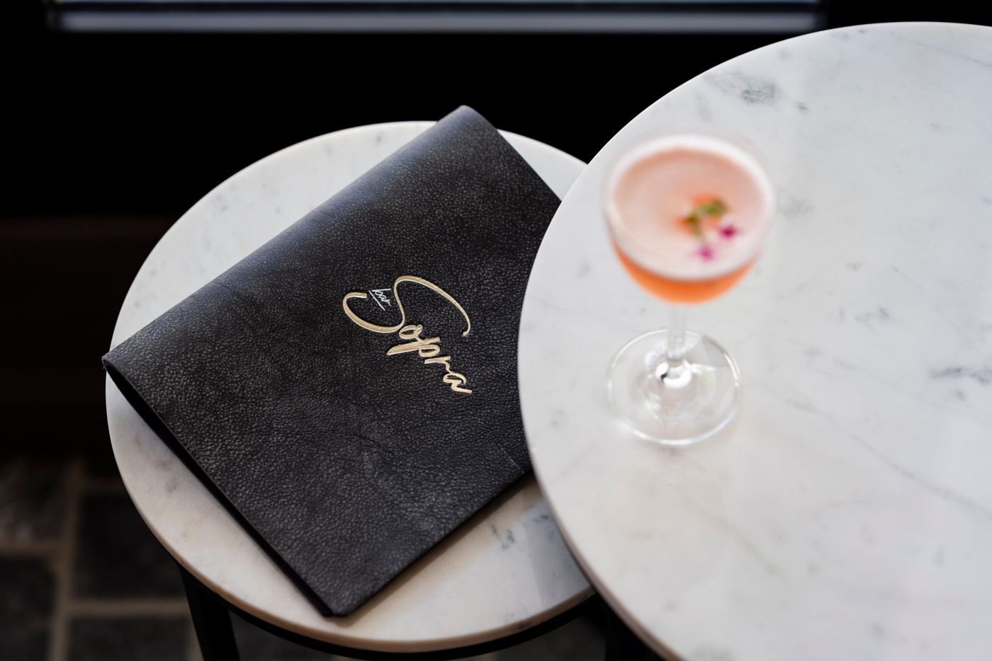 A menu and cocktail on a table at Bar Sopra in Sydney