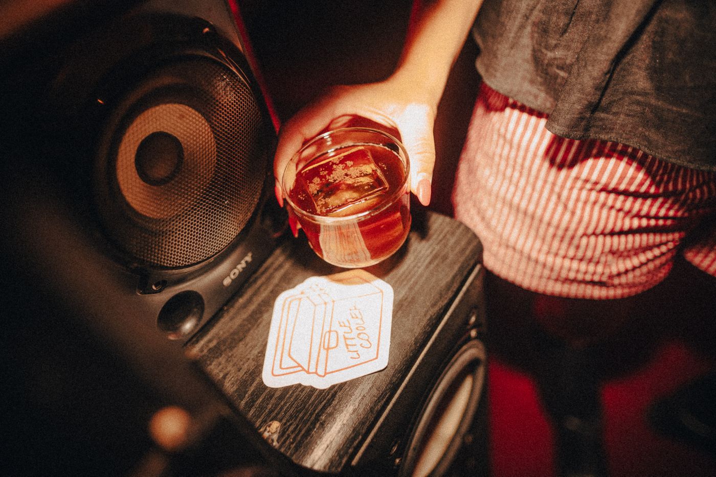 Holding a drink over speakers at Little Cooler in Sydney 