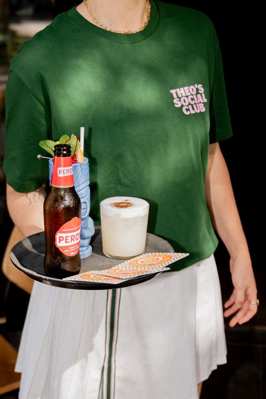 Carrying a tray with a beer and a cocktail at Theo's in Noosa