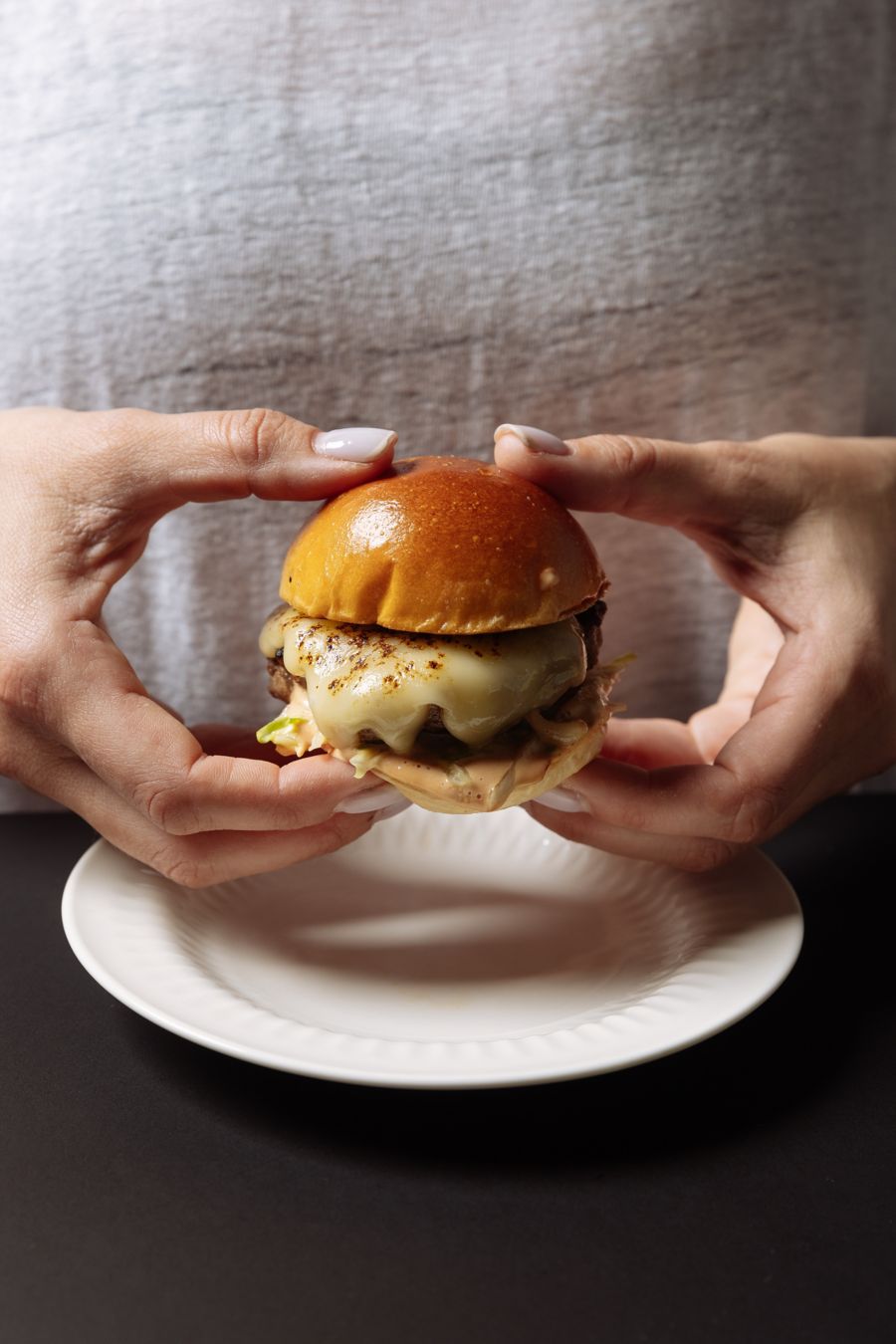 A mini burger with melted cheese served at Petite in Brisbane