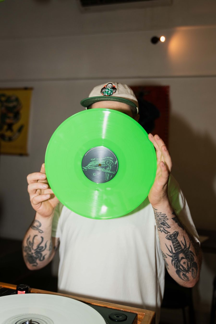 A DJ holds up a bright green record at Theo's Social Club in Noosa