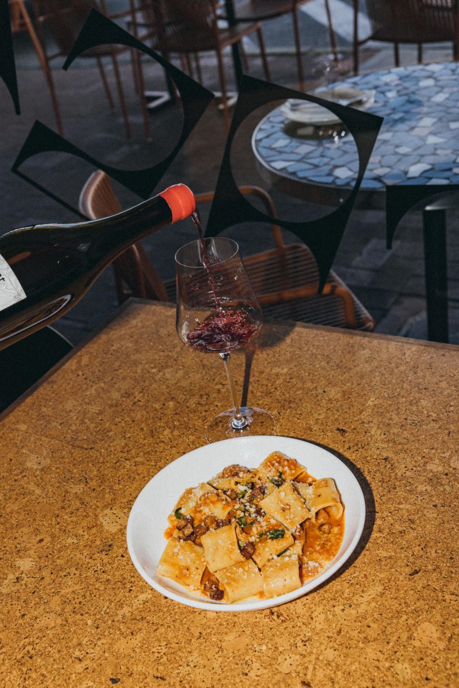 Pouring a glass of red wine with a plate of pasta 