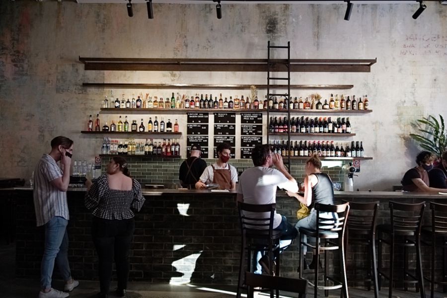 People sitting at bar counter and bartender serving drinks
