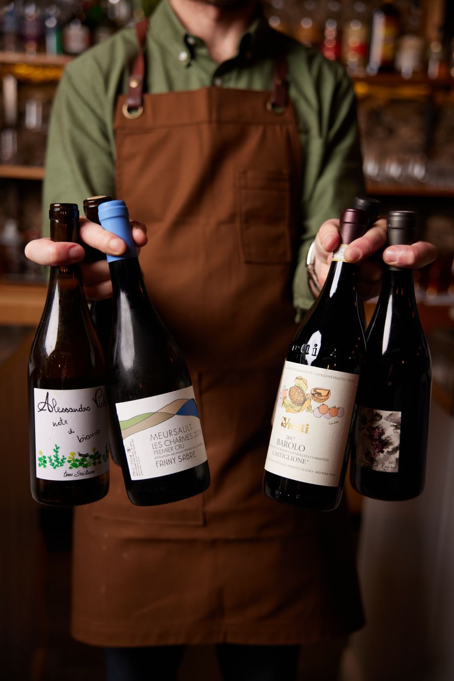 A bartender holds various wine bottles at Clever Little Tailor