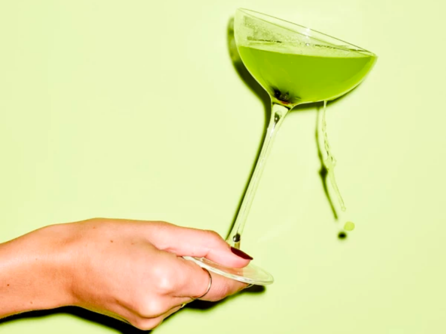 Holding a vivid green Japanese Slipper cocktail, with some spilling  