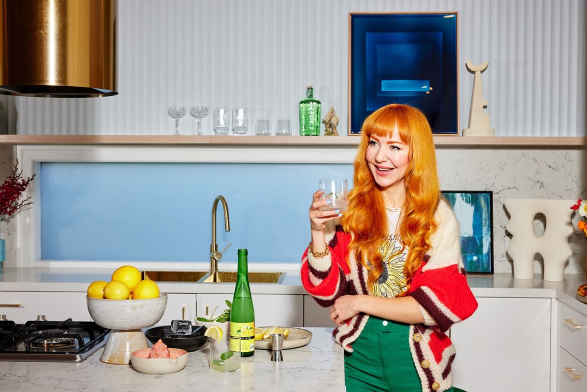 Kelly Thompson in her kitchen holding a glass of yuzushu