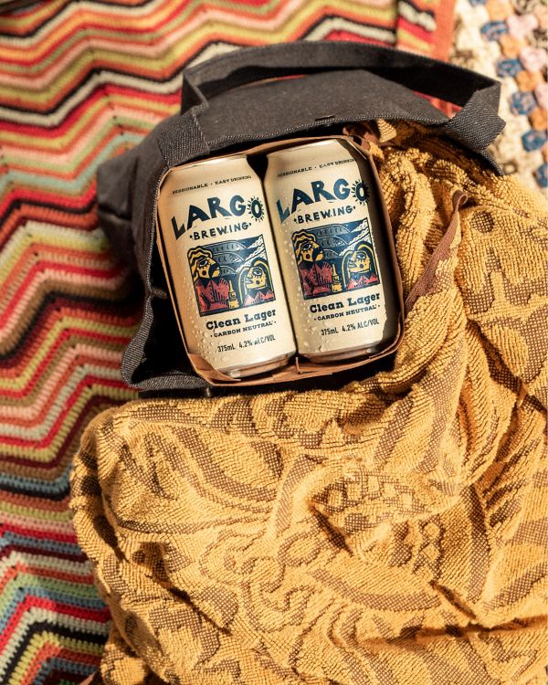 6-pack of LARGO Clean Lager inside tote bag on a towel