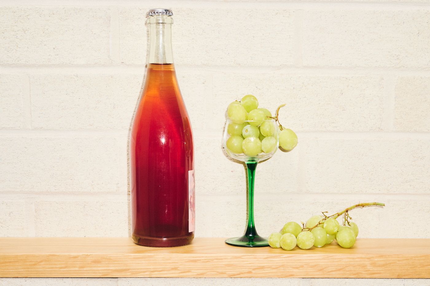 A bottle of wine next to a glass holding frozen grapes