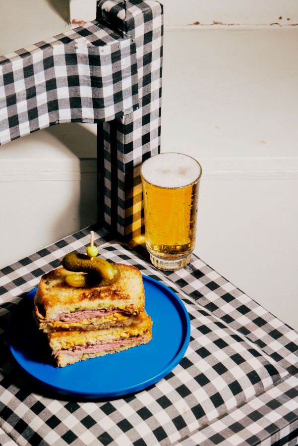 A Reuben sandwich with a glass of lager