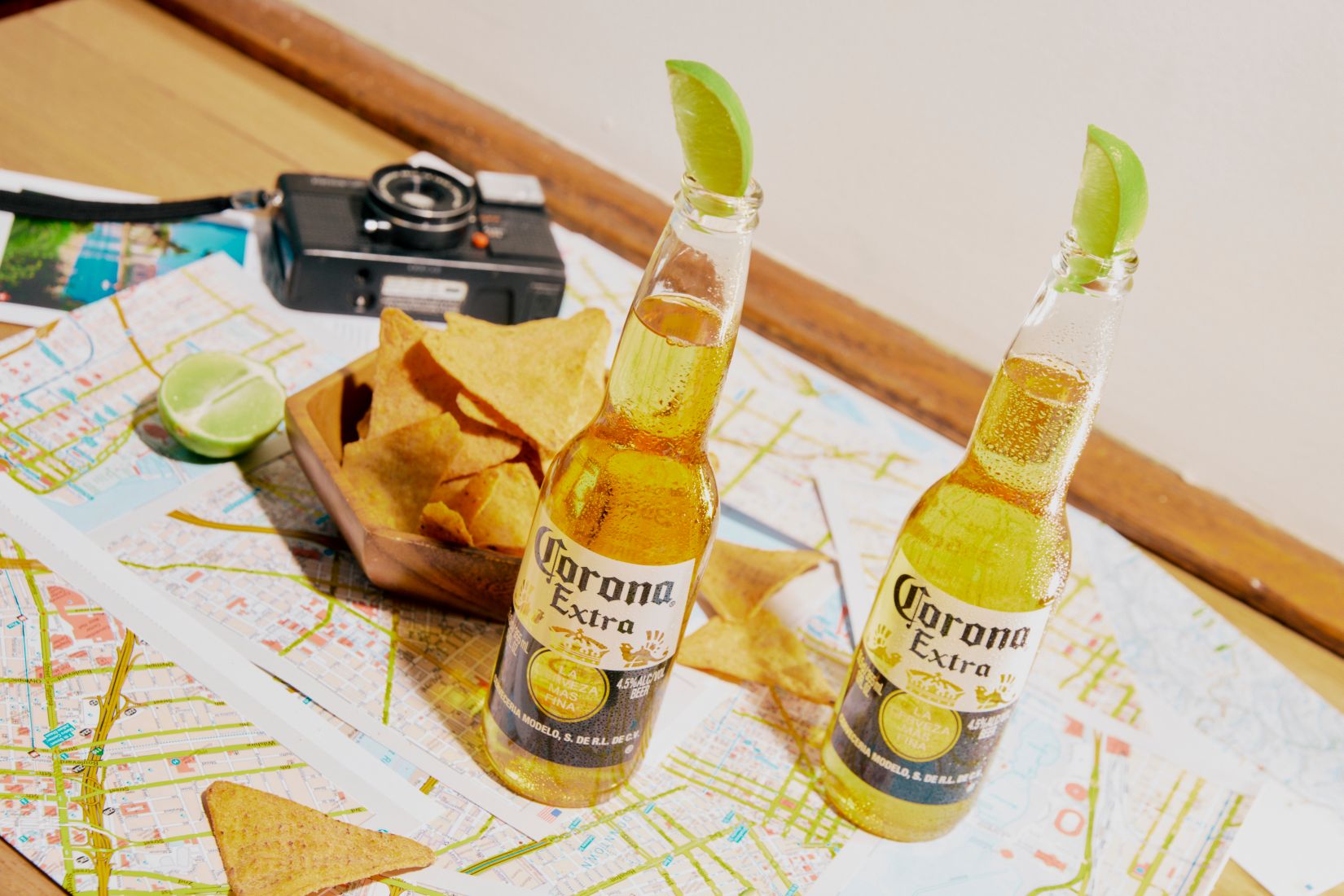 Two bottles of Corona on a map with corn chips