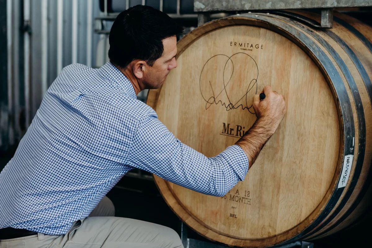 Ricky Ponting writing on barrels holding his Ponting Wine