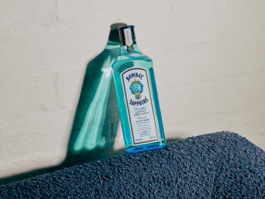 A bottle of Bombay Sapphire leaning against a wall 