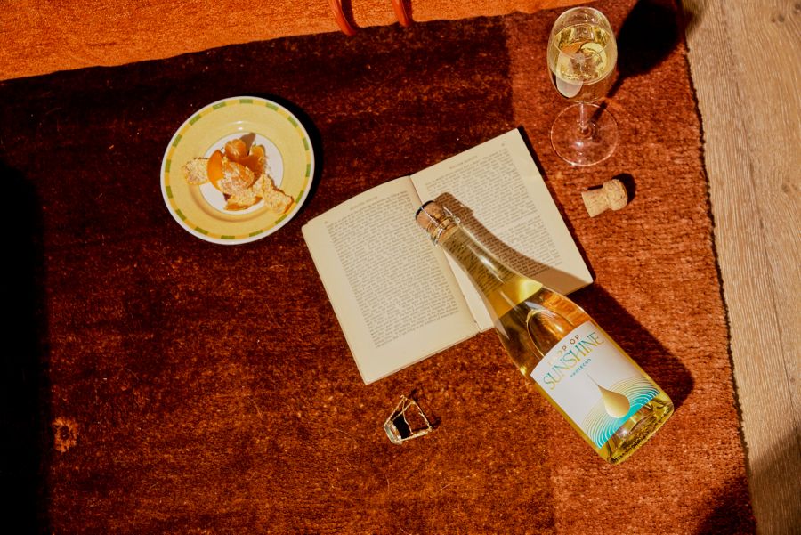 A bottle of prosecco on a table with a book