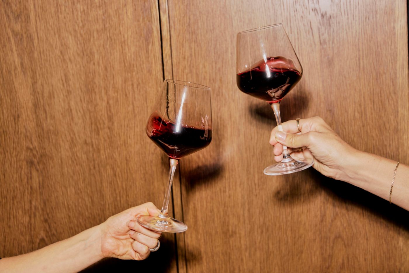 Two hands each holding a glass of red wine