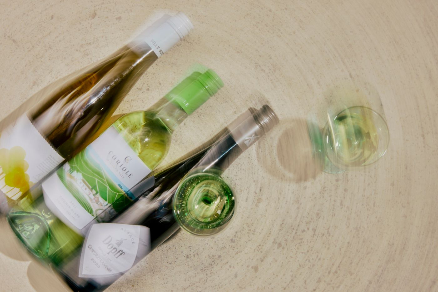 Three bottles of white wine on a table with glasses 