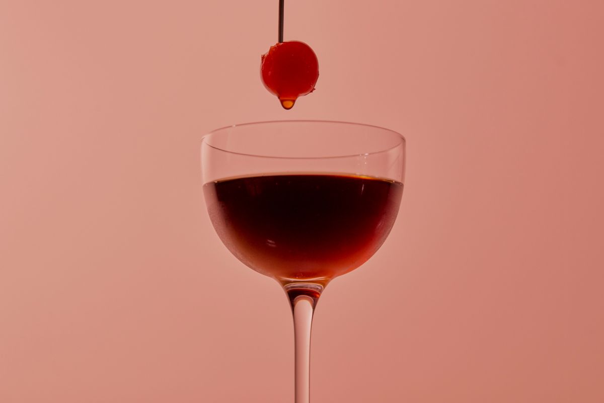 A skewered glacé cherry above the Black Manhattan cocktail  