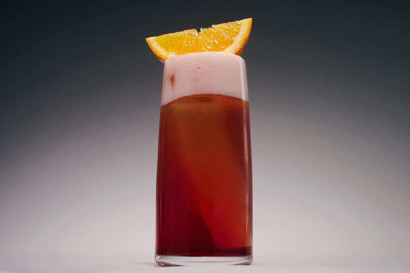 The Beericano cocktail, with a frothy top and orange garnish 