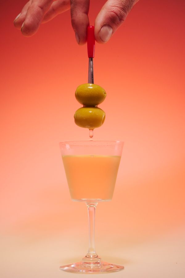 Holding skewered olives above a Dirty Martini