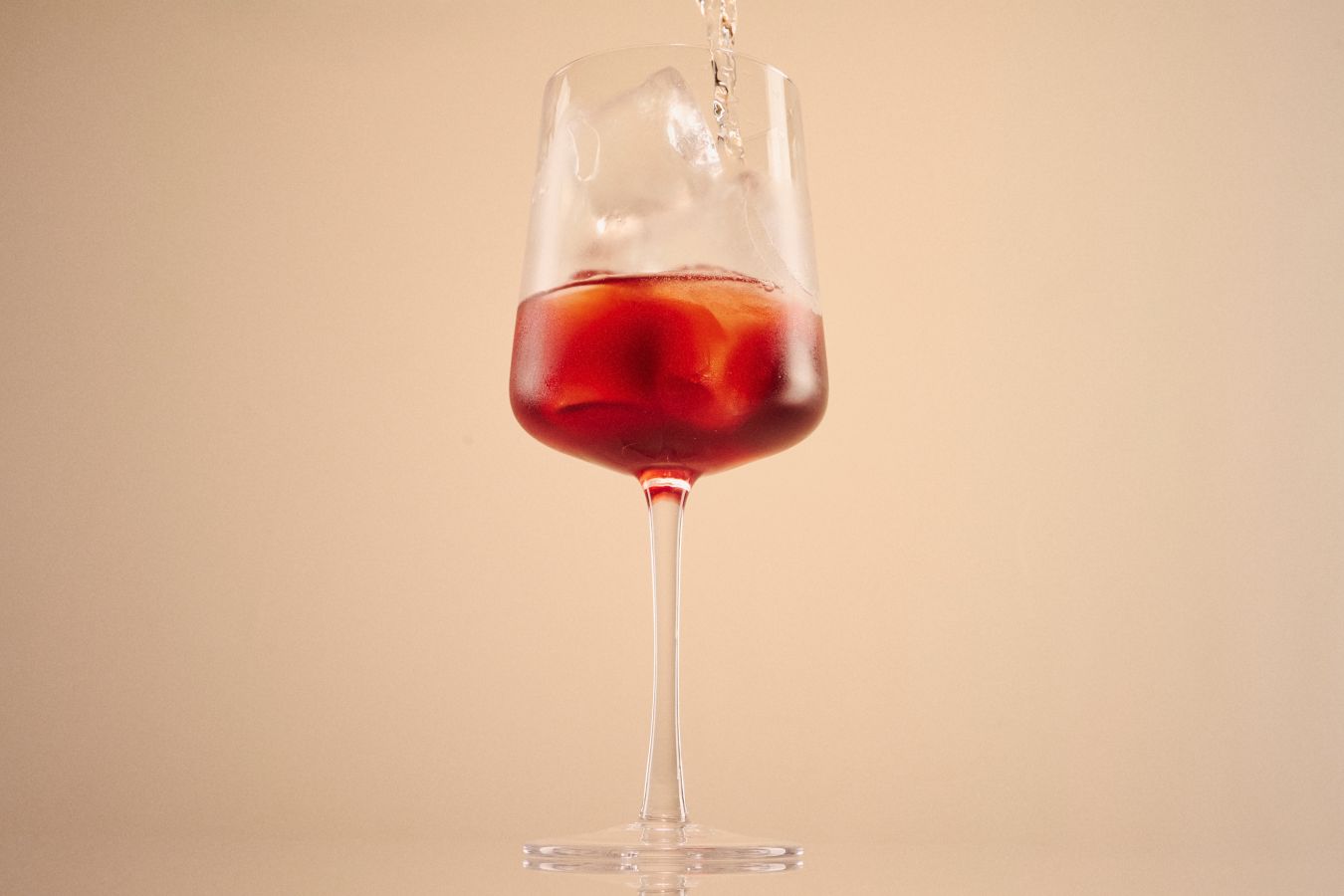 Adding soda to the Fire Cider Spritz in a wine glass 