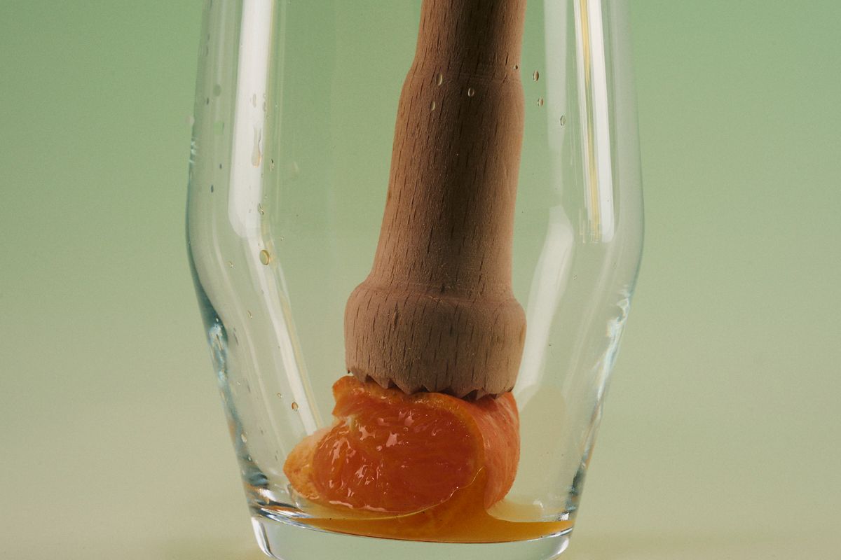 Muddling the mandarin at the bottom of the glass 