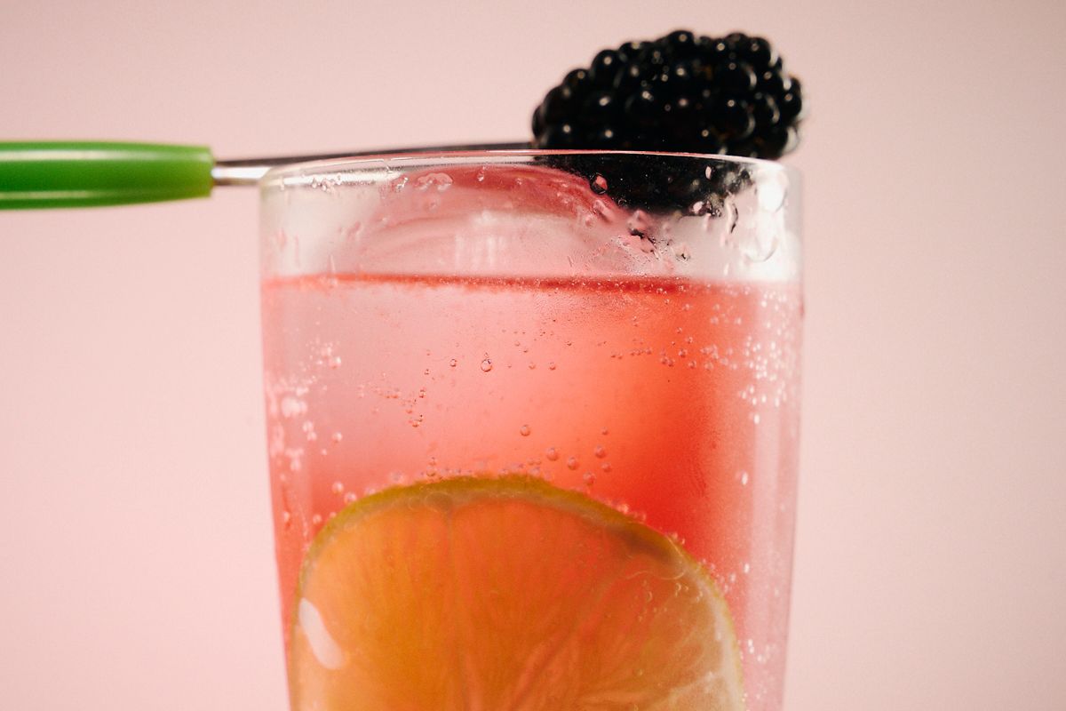 The Midnight Mimosa cocktail is garnished with a blackberry