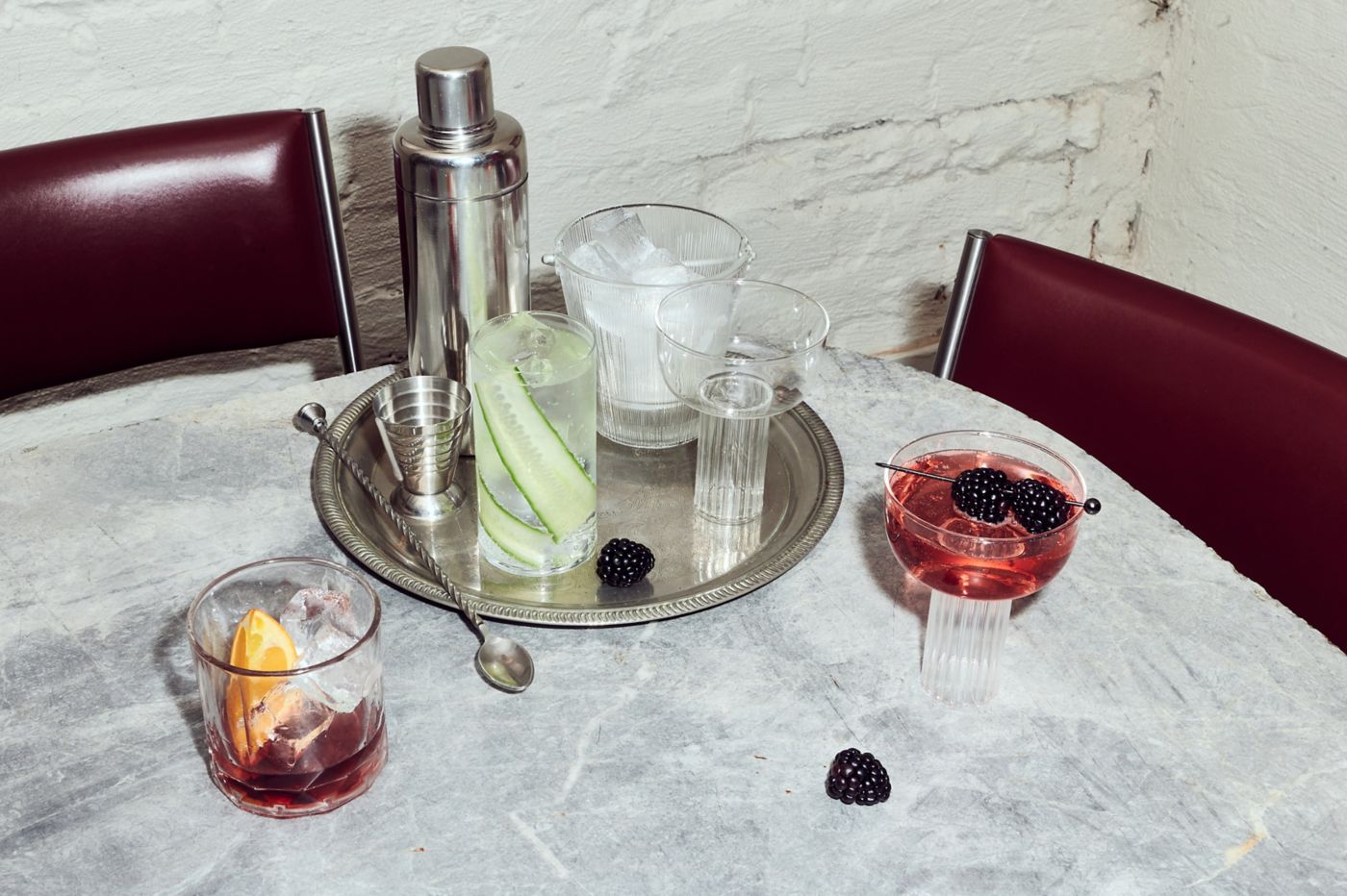 A cocktail shaker, ice and non-alcoholic drinks on a table 