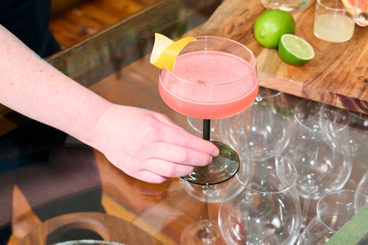 Holding the bright pink Siesta tequila-based cocktail