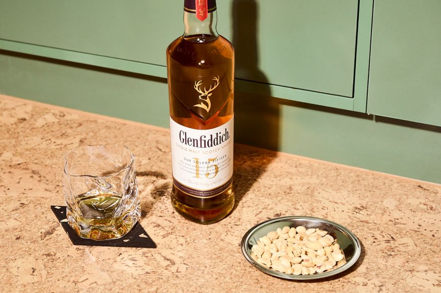 A bottle of Glenfiddich 15 Year Old with nuts and a glass of whisky