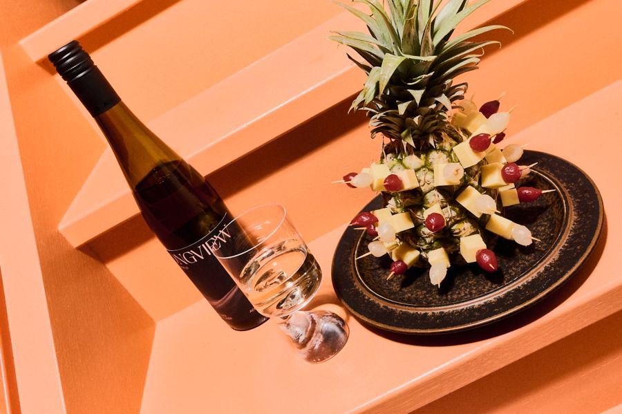 Cheese and pickled onion skewers in a pineapple, with a bottle of Longview Grüner Veltliner