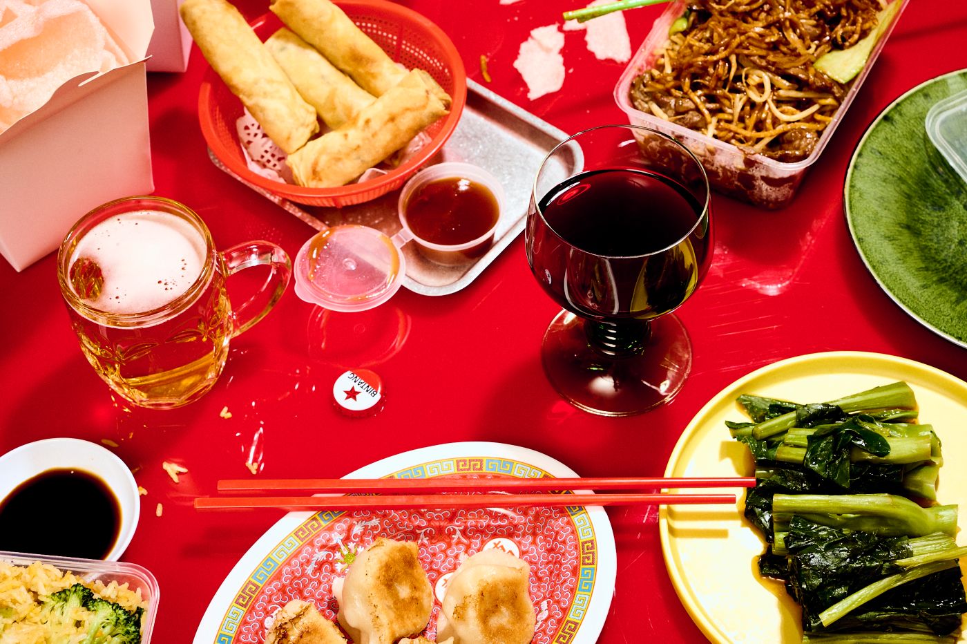 A spread of Chinese dishes with a glass of red wine and beer 