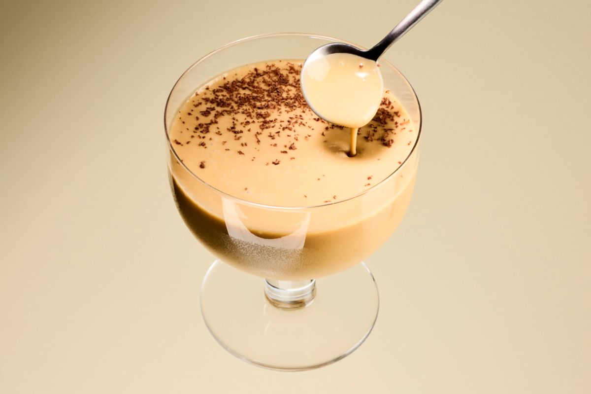 Dipping a spoon into a Rum and Dulce cocktail, garnished with chocolate shavings