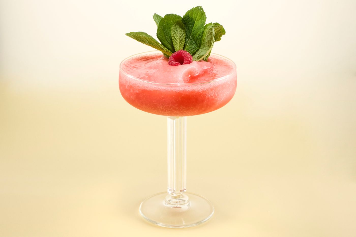 The Frozen Raspberry Cosmo cocktail garnished with mint and a raspberry
